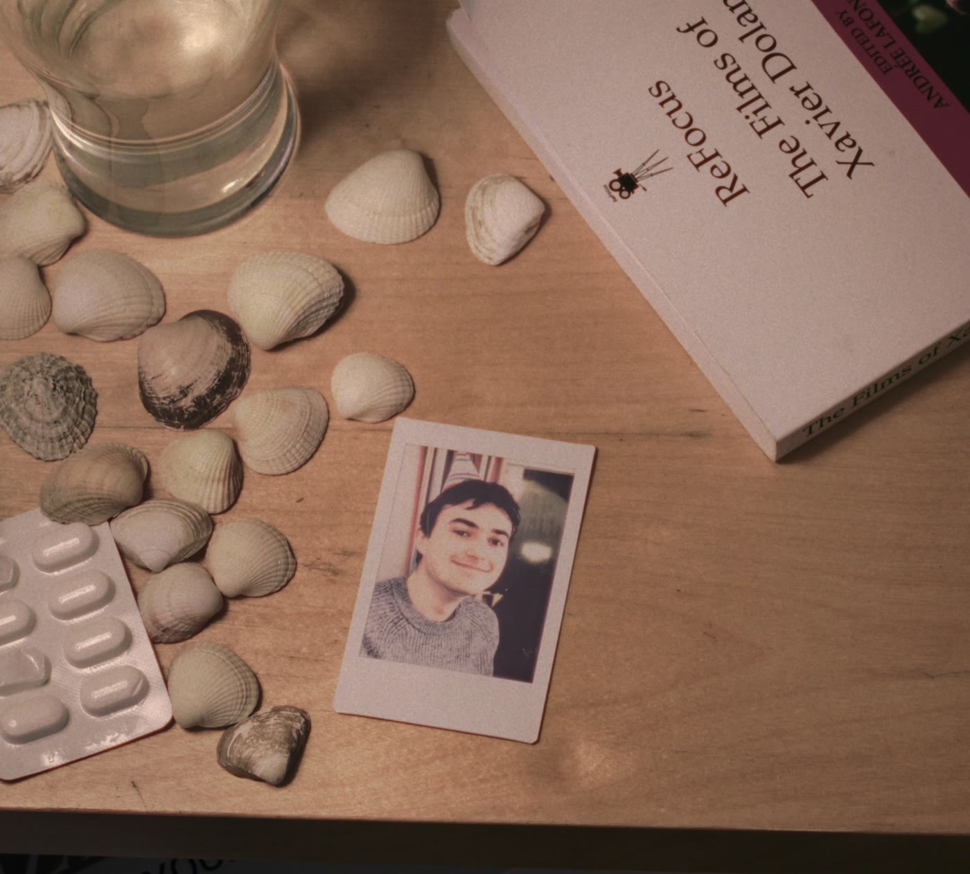 Shells, a polaroid and a book on a wooden table