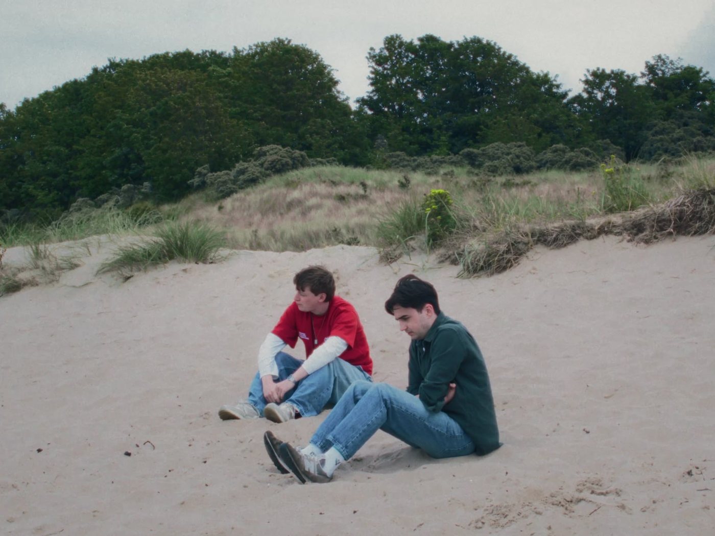 Two boys sitting on the sand among the dunes